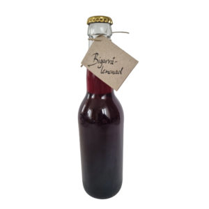 Flaska med bigarrålemonad med mörkröd färg och enkel etikett.