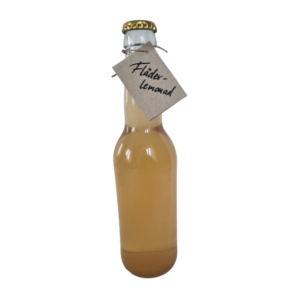 Flaska med fläderlemonad med ljus färg och naturlig etikett.