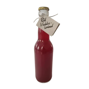 Flaska med röd vinbärslemonad med naturlig färg och enkel etikett.